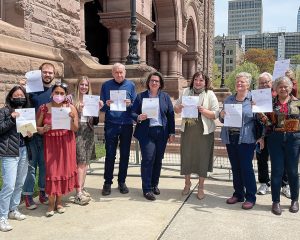 ONA President Erin Ariss stands with our allies outside Queen's Park, holding citations for shouting “shame” in the Ontario Legislature when Bill 60 passed on May 8, 2023.
